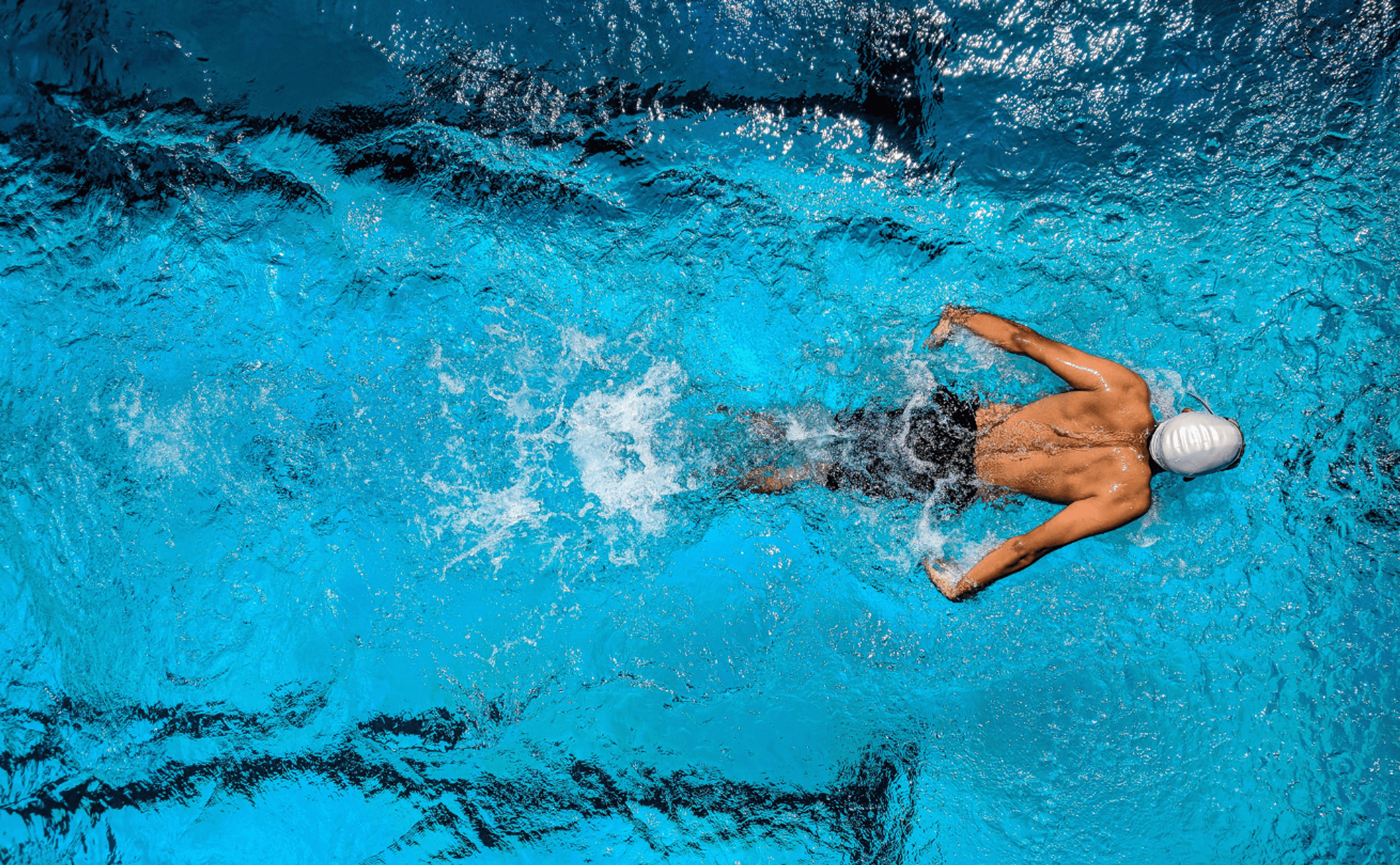 Man doing butterfly stroke and swimming laps in athletic pool.