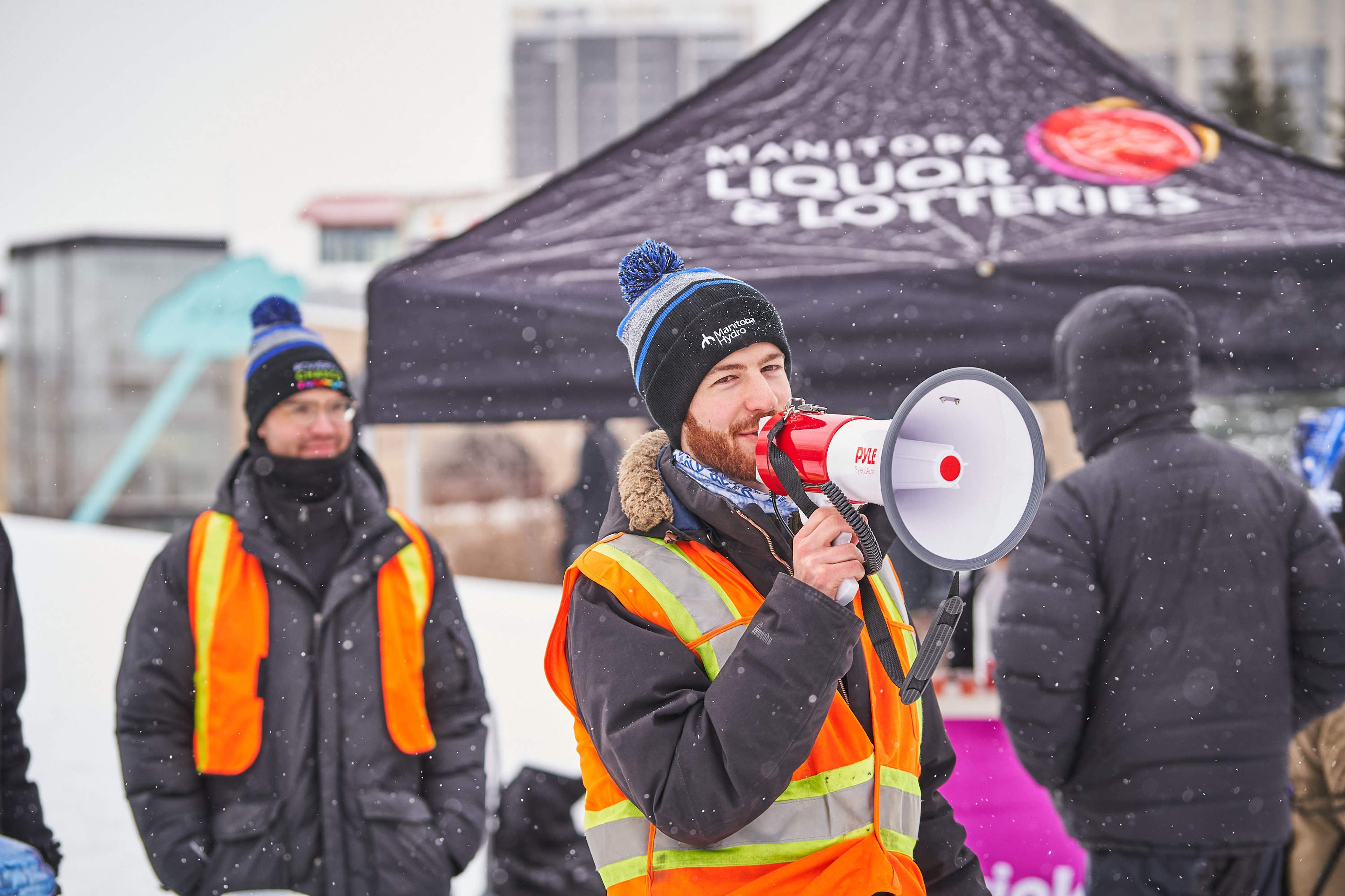 Luke Rempel speaks into a loudspeaker in a snowy landscape. 