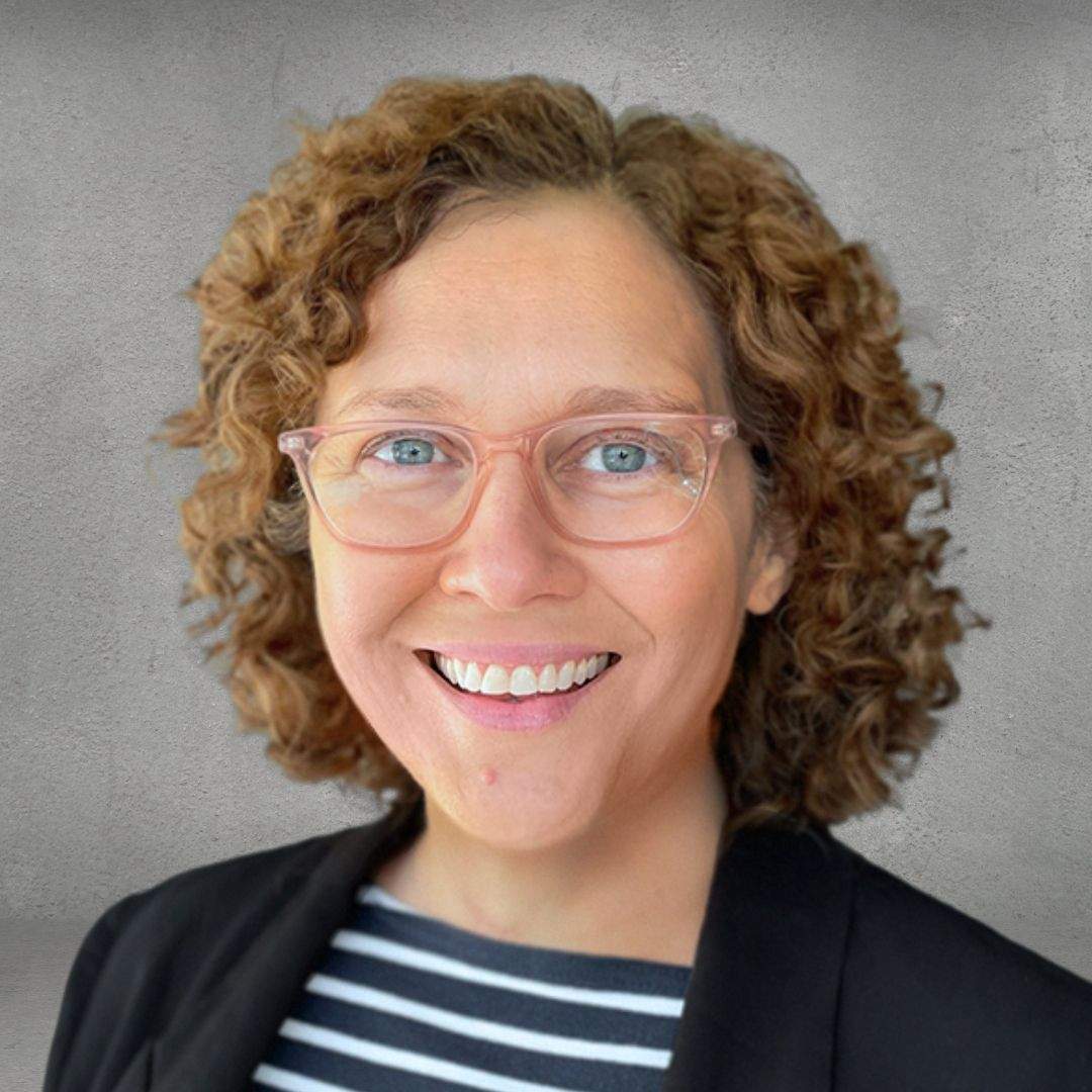 Curly-haired brand strategist and writer in a striped Breton top leads clients in a branding workshop via Zoom meeting.