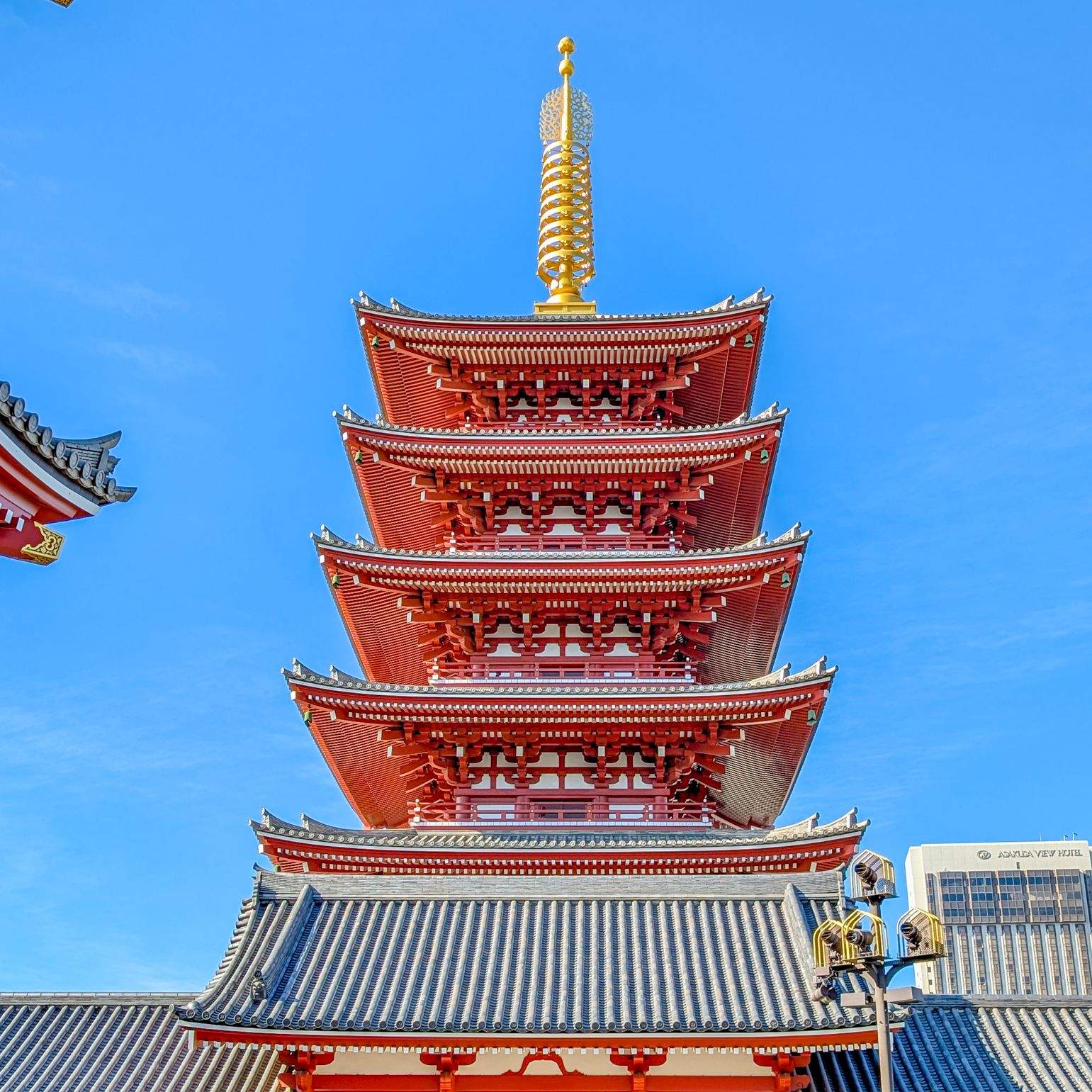 The five-story pagoda of Sensō-ji Temple in Asakusa, Tokyo, with its red and gold exterior against a clear blue sky.