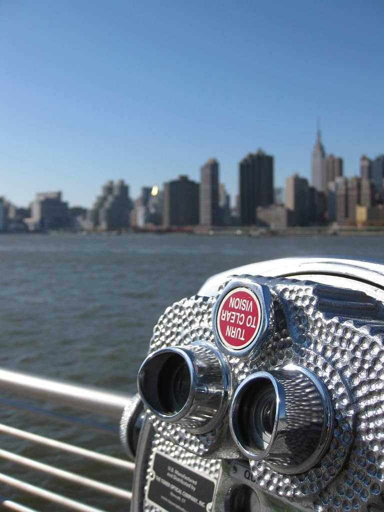 Coin-operated binocular viewer facing Manhattan’s skyline from Long Island City, with gantries in the foreground.