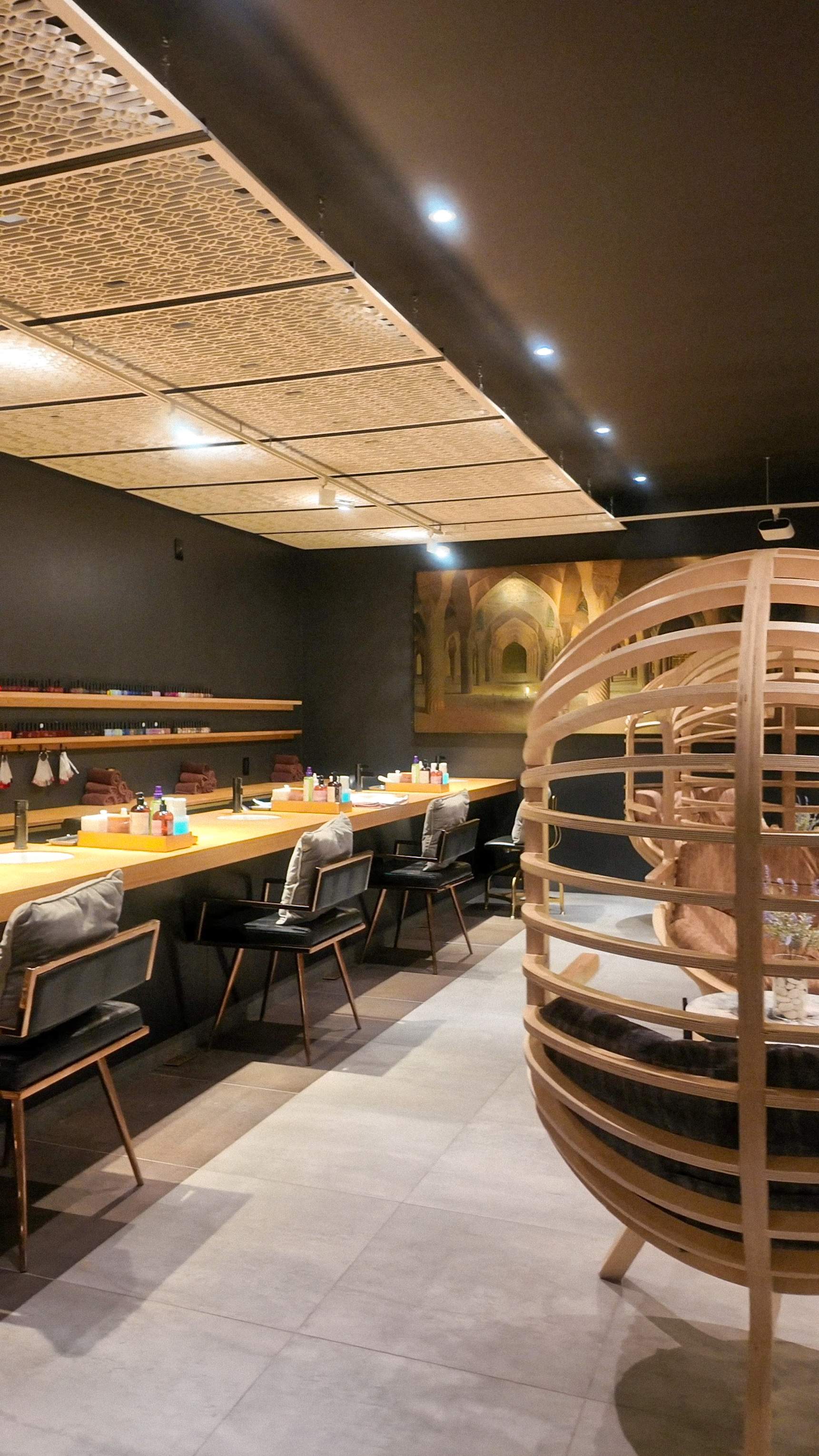 The manicure and pedicure lounge at Hammam Spa, featuring long wooden tables, comfortable chairs, and an East Asian-inspired ambiance with i