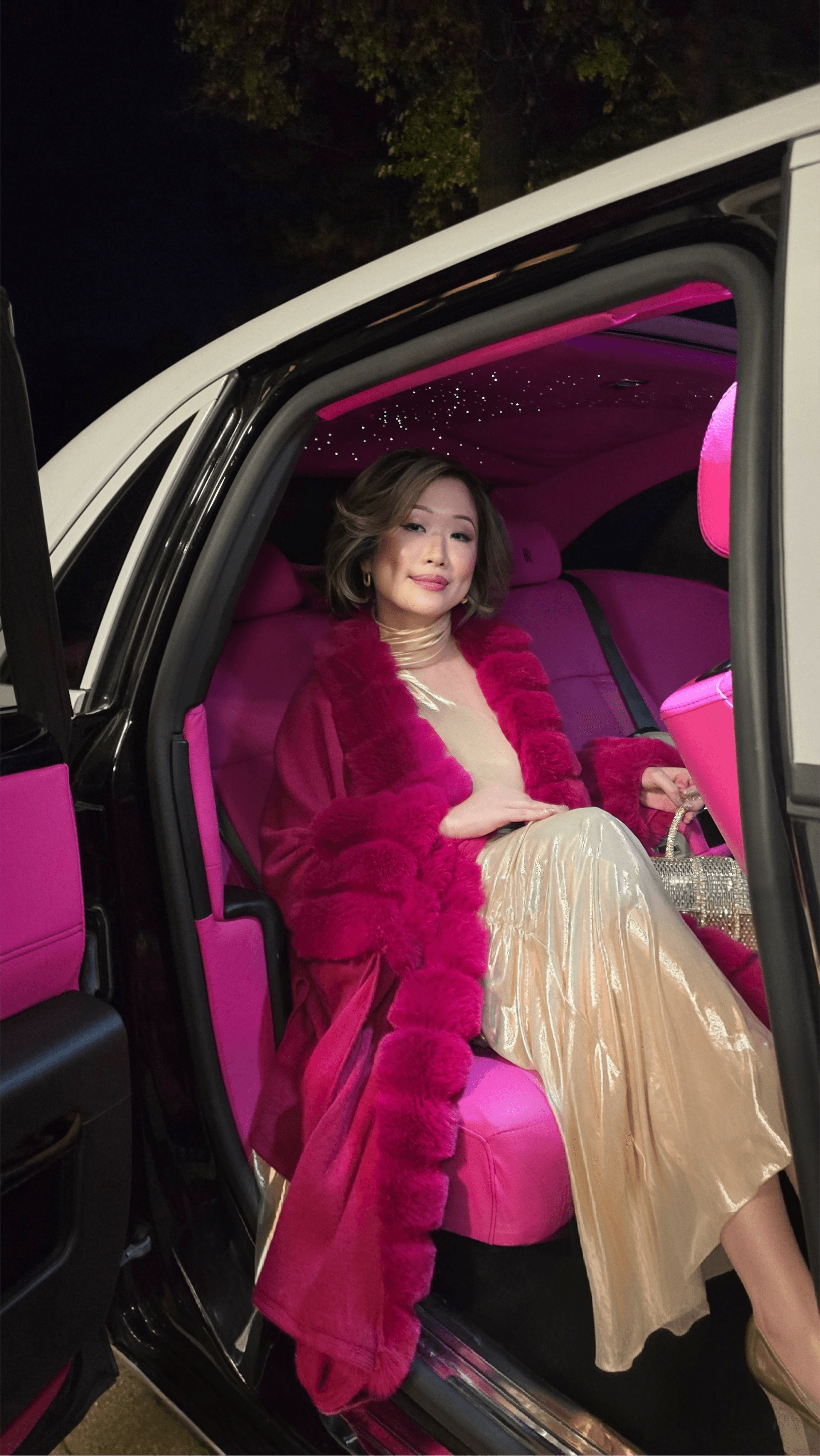 Betty Lam (@itsbettylam) looking glamorous in a pink fur coat ,gold dress, sitting inside a Rolls Royce with a custom pink leather interior