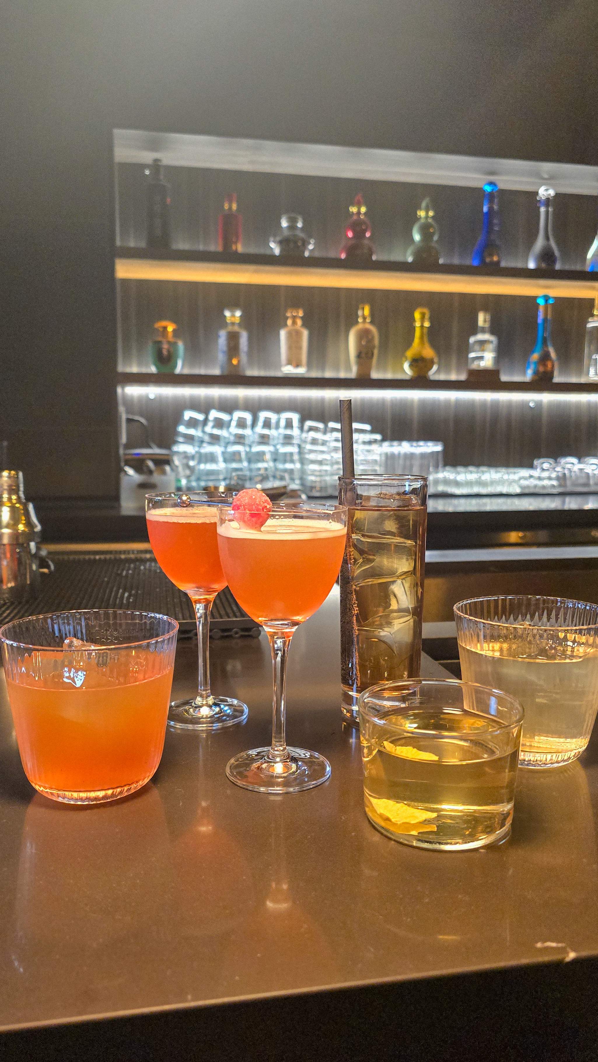 Four modern Baijiu cocktails on a sleek bar top at Hong Shing Toronto, including the Legend Tao and a refreshing highball drink.