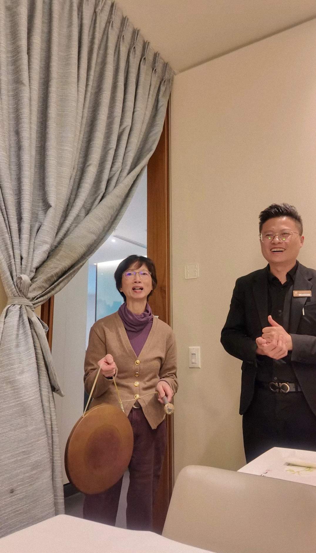 Woman tapping a small ceremonial gong during the Peking duck presentation at QJD Peking Duck Markham private dining room with manager Daniel