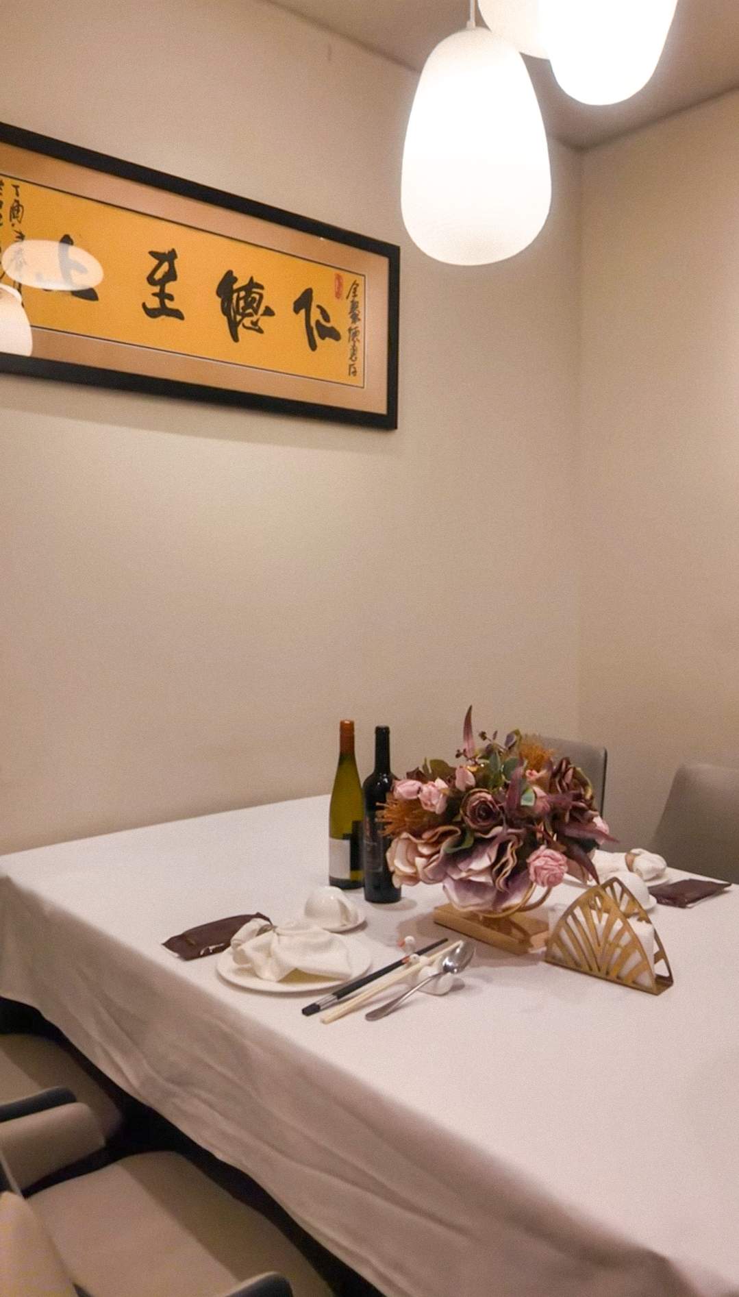 Intimate private dining room at QJD Peking Duck Markham elegantly set with white linen wine bottles flower centrepiece and QJD gold calligra