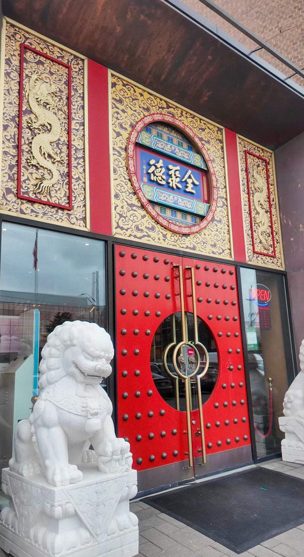 Exterior of QJD Peking Duck restaurant in Markham Ontario on Woodbine Avenue featuring red imperial doors gold dragon carvings white stone f