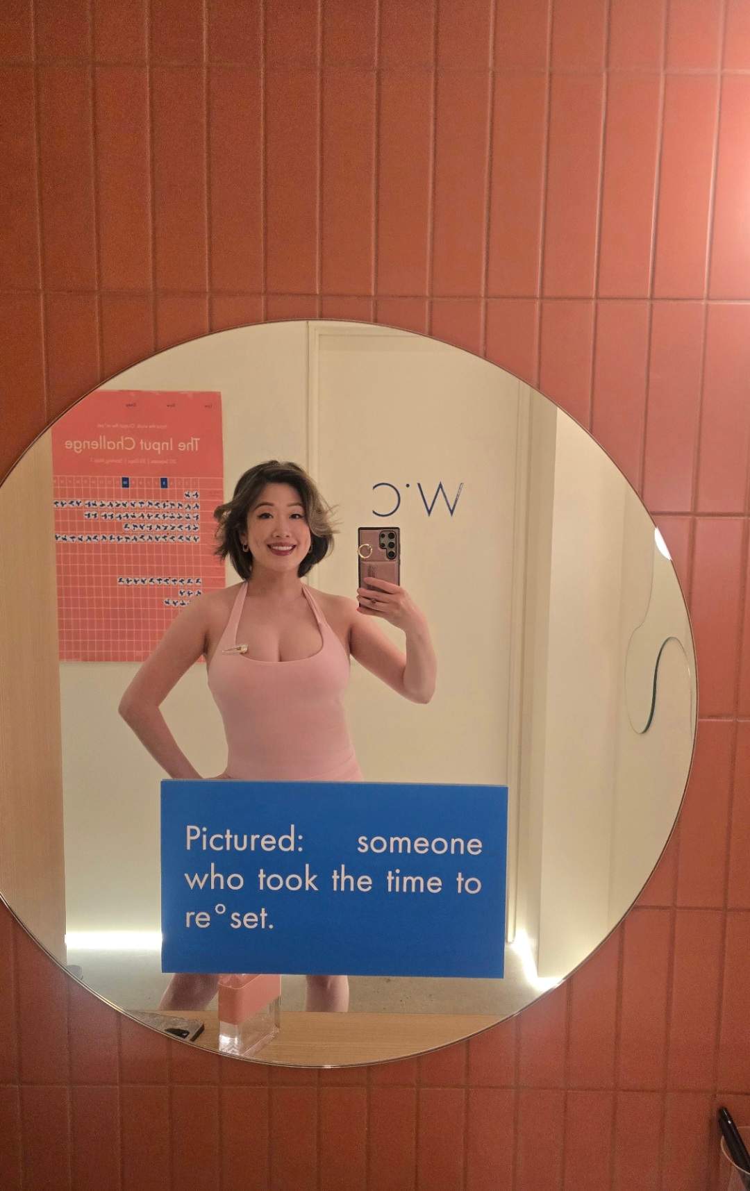Mirror selfie at LSD°R Summerhill studio bathroom with branded reset sign, pink tiles, post reformer Pilates class in Toronto