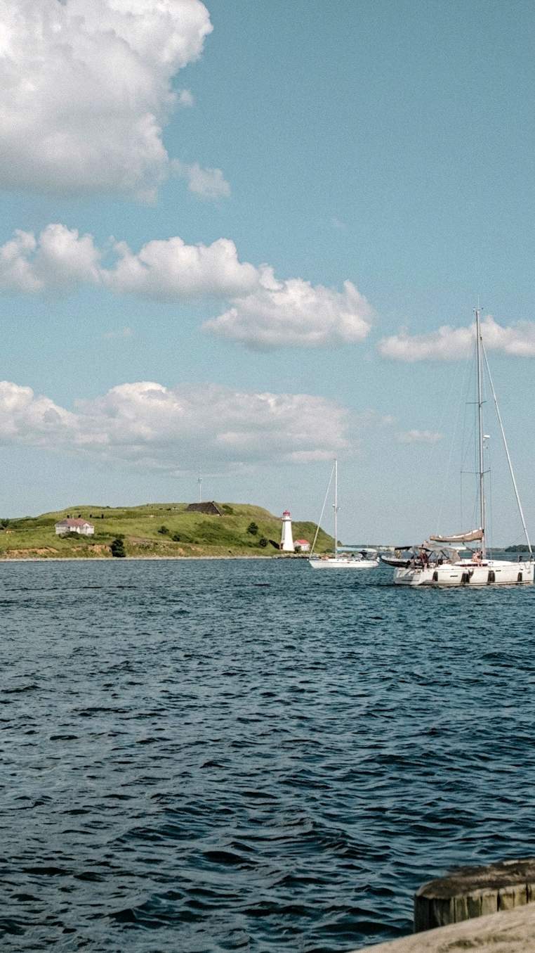 View of Georges Island and its historic lighthouse in the Halifax Harbour on a sunny day with sailboats passing by