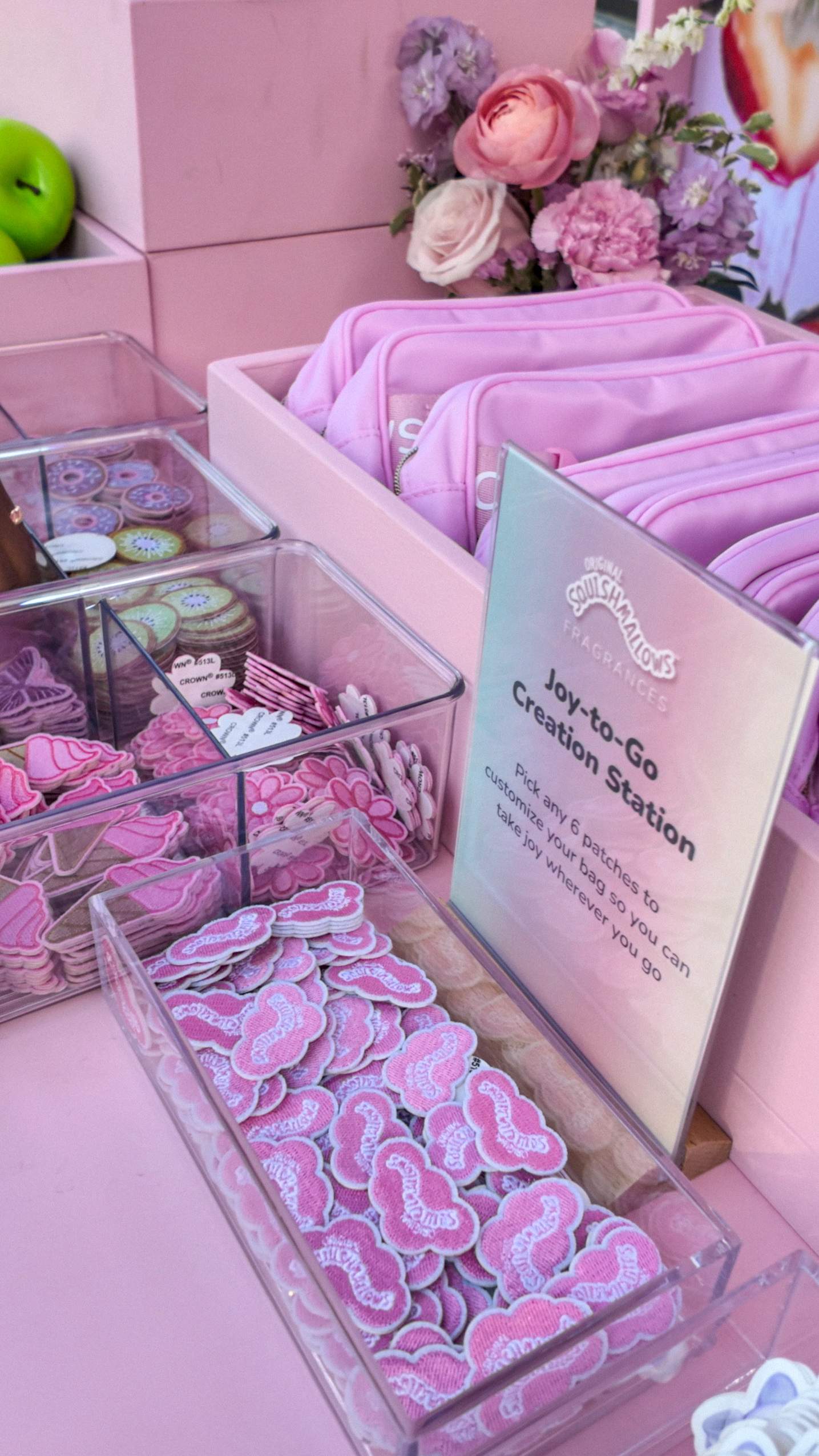 Joy-to-Go Creation Station at the Squishmallows Fragrances event, with pink patches, peaches and pouches for guests to customize.