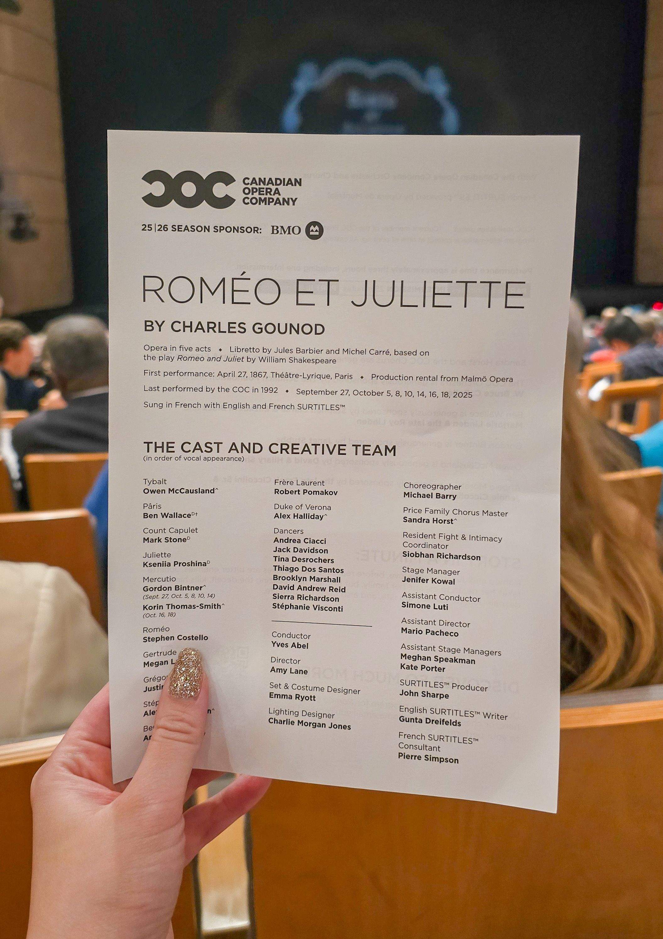 Hand with sparkling manicure holding a program for the Canadian Opera Company's Roméo et Juliette, showing cast details inside the theatre
