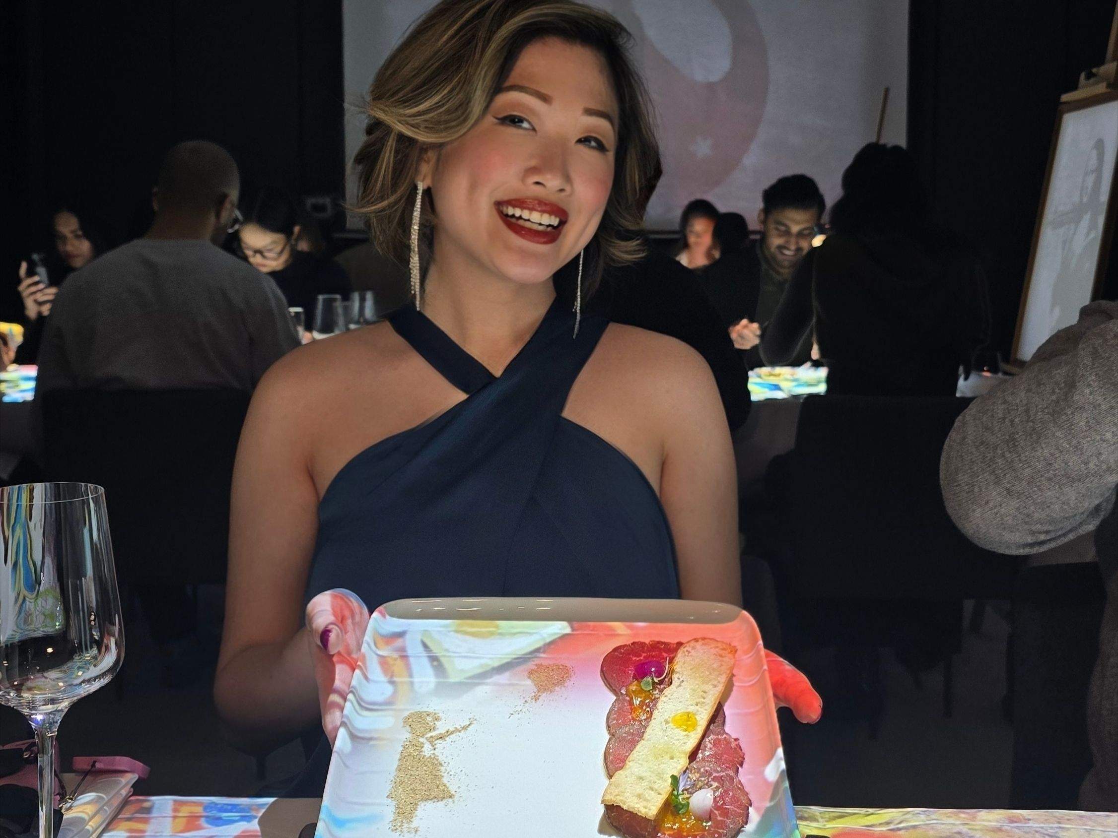  Betty holding the Picasso-inspired trout dish at the 7 Paintings immersive dining show in Toronto.  