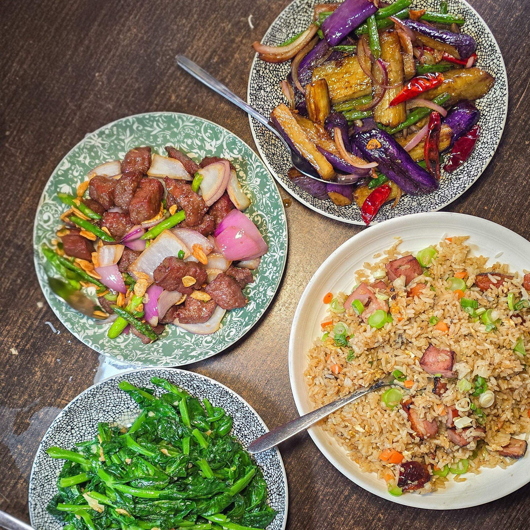 Overhead view of authentic Chinese dishes at Hong Shing Toronto, including duck fried rice, garlic greens, and spicy eggplant.