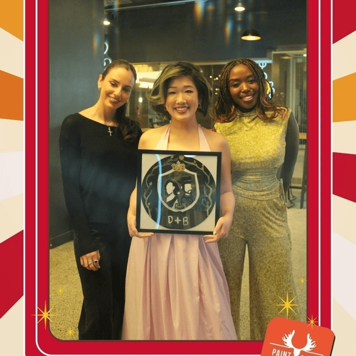 Close-up of three friends holding up their custom painted vinyl records while standing in front of a neon light wall at Paint Cabin