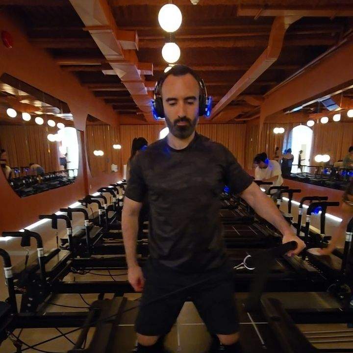 Man doing reformer Pilates class at LSD°R Studios Toronto Summerhill wearing headphones on custom LSDR reformer machine
