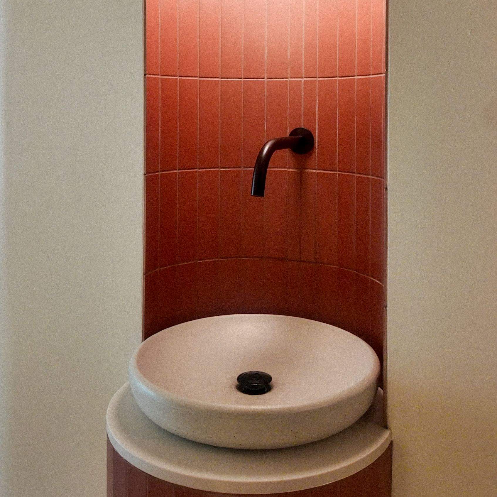 Terracotta tiled washroom with stone vessel sink and globe pendant light at LSD°R Summerhill boutique fitness studio Toronto